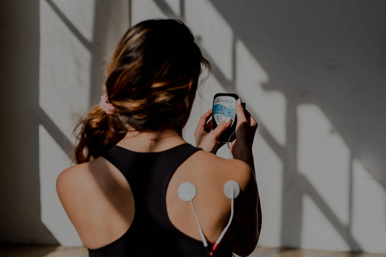 photo of a woman using the biomodulator plus with 2 round conductive pads on her back