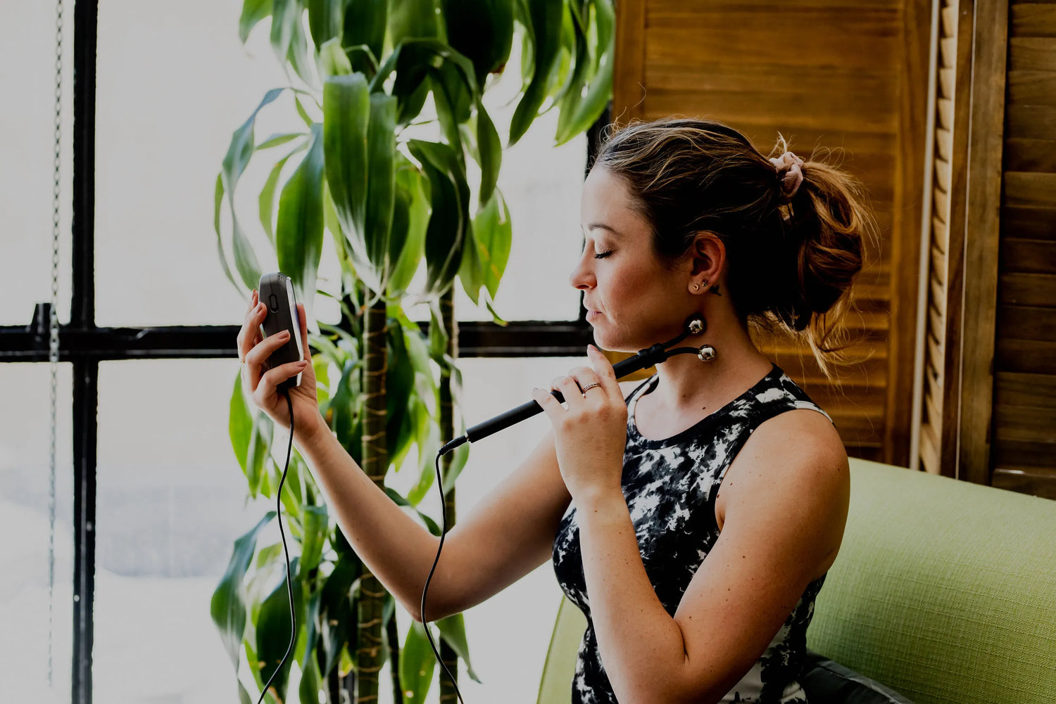 woman using the y-electrode on the side of her neck while holding the biomodulator pro