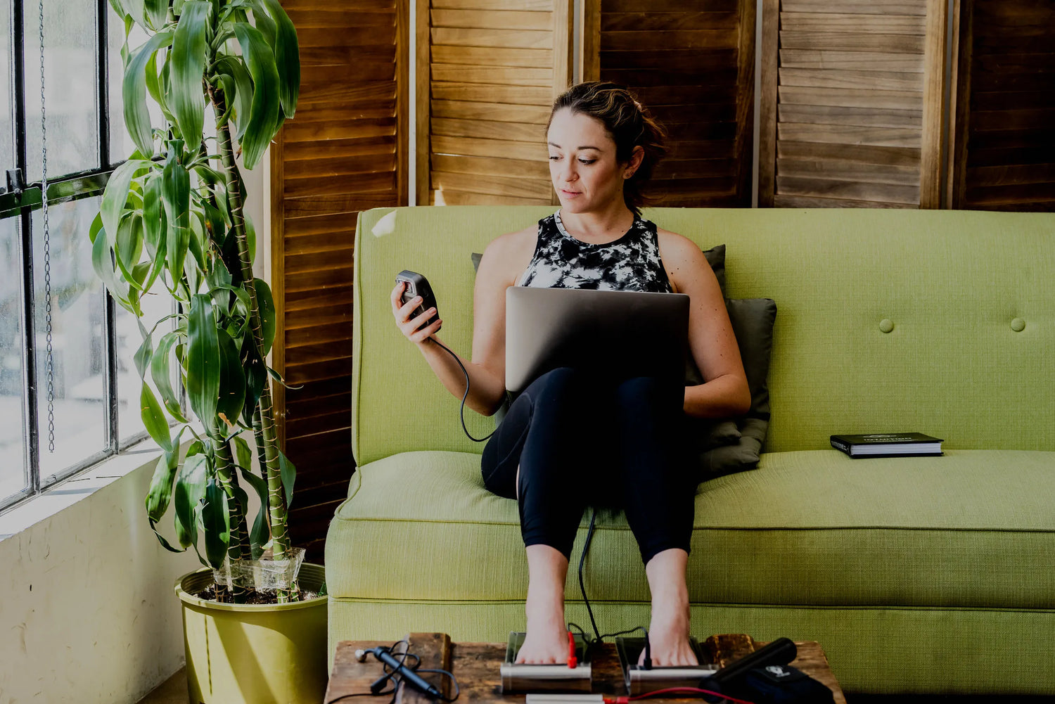 woman sitting on a couch working on her laptop while using the footplates 