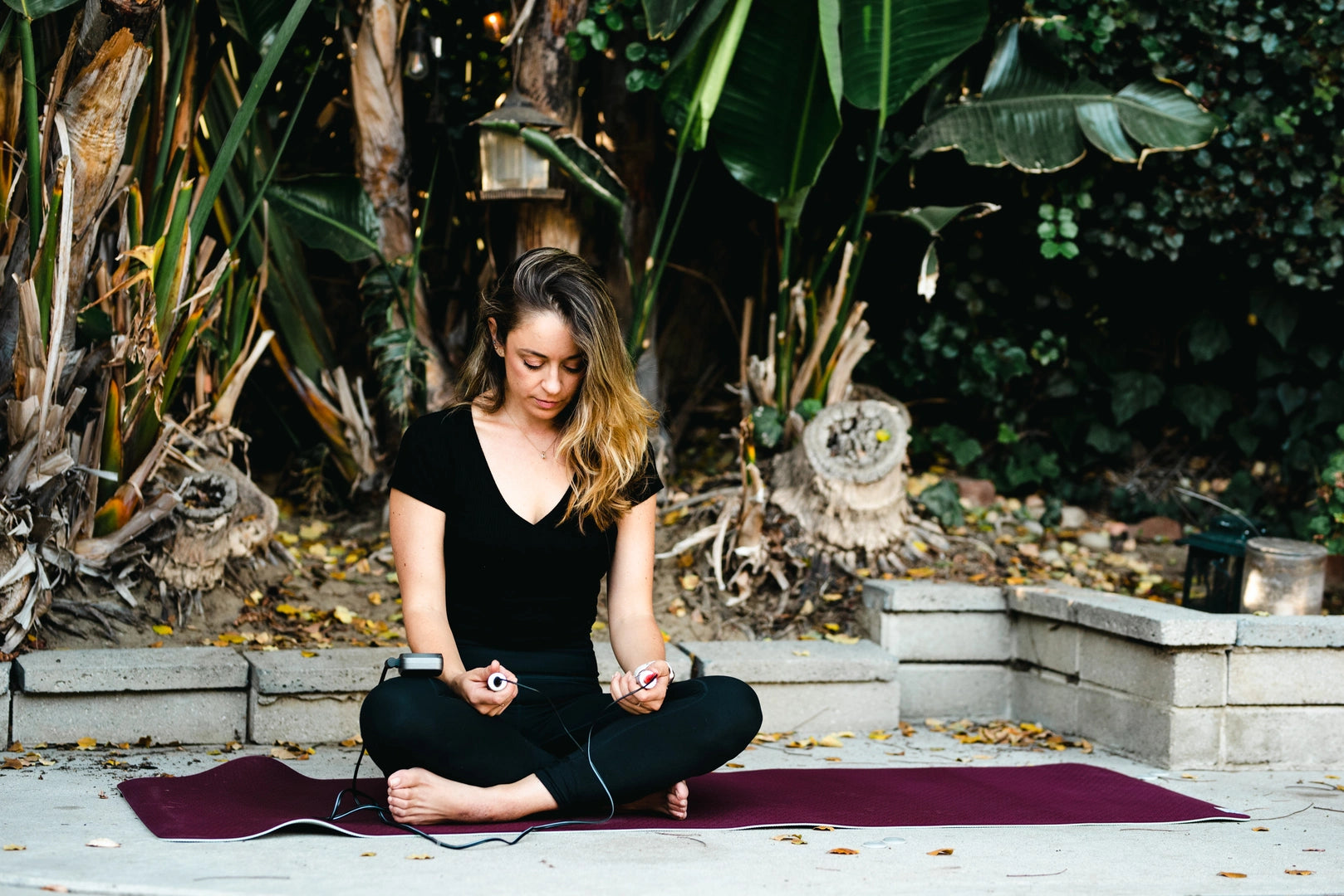 woman sitting cross legged on a yoga mat using the hand grips